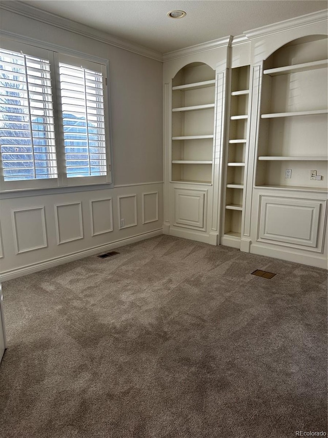 carpeted empty room with ornamental molding and built in features