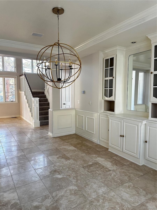 unfurnished dining area with crown molding and a chandelier