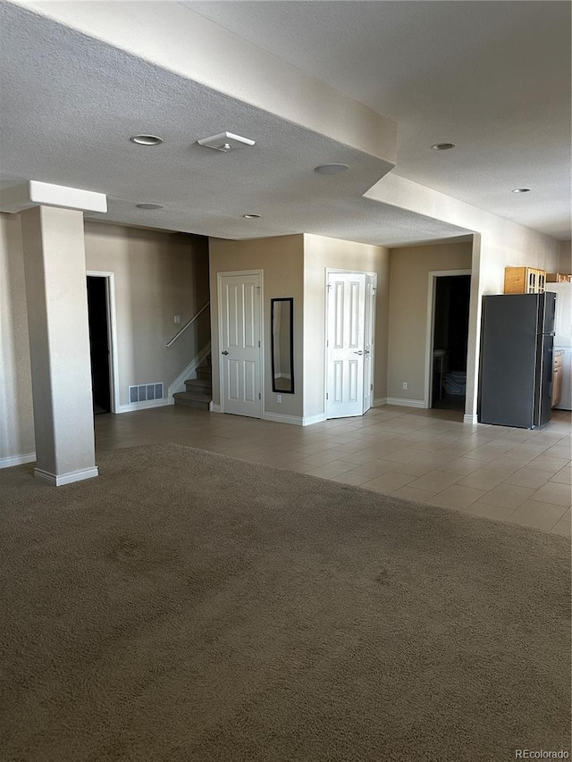 spare room featuring light carpet and a textured ceiling