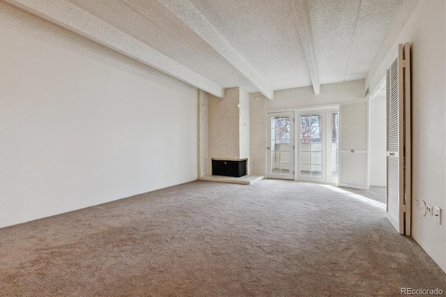 unfurnished living room with beam ceiling, a brick fireplace, carpet, and a textured ceiling