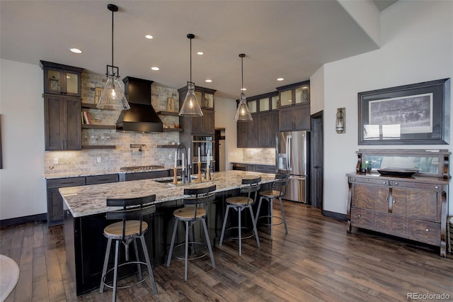 kitchen with glass insert cabinets, custom range hood, dark brown cabinetry, and stainless steel fridge with ice dispenser