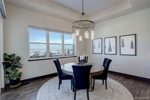 dining room featuring baseboards, a tray ceiling, and dark wood finished floors