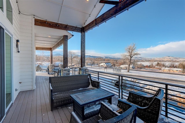 snow covered deck with outdoor lounge area and a mountain view