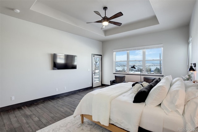 bedroom featuring ceiling fan, baseboards, a raised ceiling, and dark wood finished floors