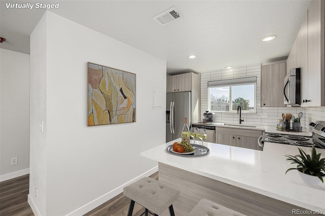 kitchen featuring visible vents, decorative backsplash, appliances with stainless steel finishes, light countertops, and a sink