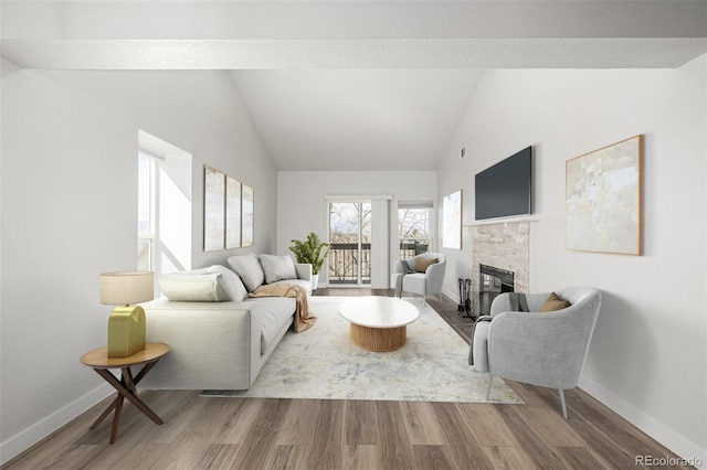 living room with high vaulted ceiling, baseboards, wood finished floors, and a glass covered fireplace