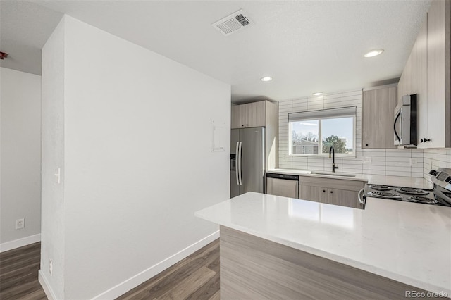 kitchen with a sink, appliances with stainless steel finishes, backsplash, and visible vents