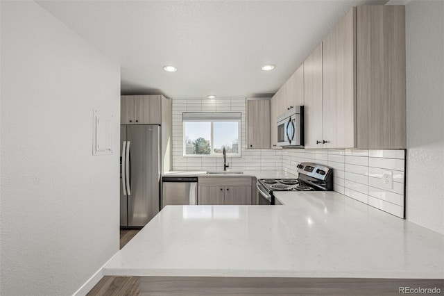 kitchen featuring light stone counters, appliances with stainless steel finishes, decorative backsplash, and a sink