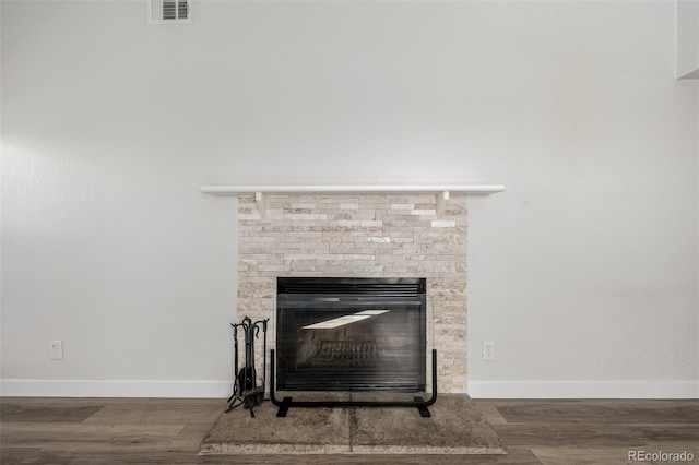 room details with a fireplace, wood finished floors, visible vents, and baseboards