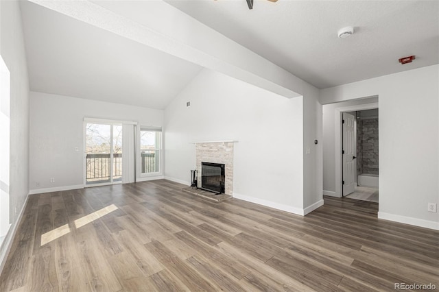 unfurnished living room featuring lofted ceiling, a fireplace, baseboards, and wood finished floors