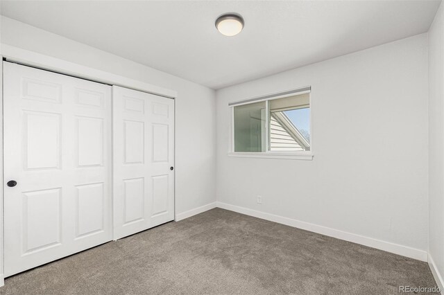 unfurnished bedroom with carpet, a closet, and baseboards