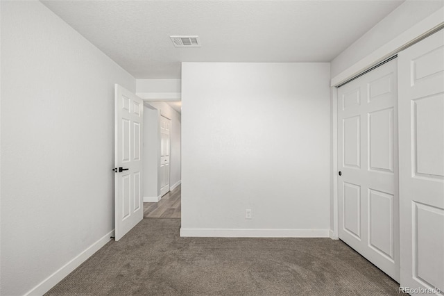 unfurnished bedroom featuring carpet floors, a closet, visible vents, and baseboards