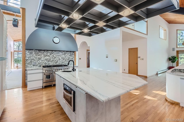 135 Poorman Rd, Boulder, CO 80302 - kitchen featuring stainless steel appliances, arched walkways, range hood, tasteful backsplash, and light wood-type flooring