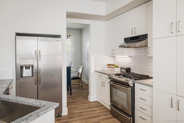 14000 Winding River Ct Unit T3, Broomfield, CO 80023 - kitchen with under cabinet range hood, appliances with stainless steel finishes, light stone countertops, backsplash, and wood finished floors