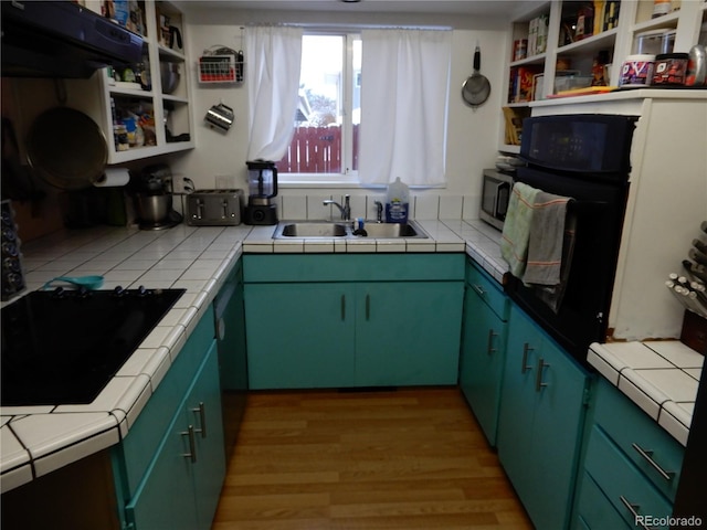 kitchen with tile counters, green cabinetry, sink, and light hardwood / wood-style flooring