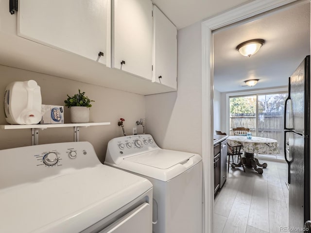 laundry area featuring cabinets, hardwood / wood-style flooring, and washing machine and clothes dryer