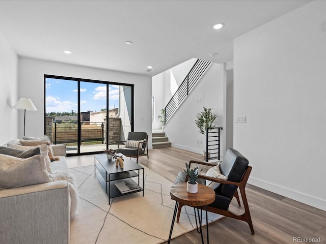 living room with stairs, recessed lighting, light wood-style floors, and baseboards