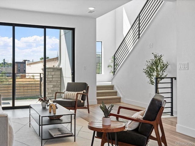 sitting room featuring stairs, light wood-type flooring, and baseboards