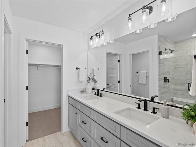 full bathroom featuring double vanity, a shower stall, a spacious closet, and a sink