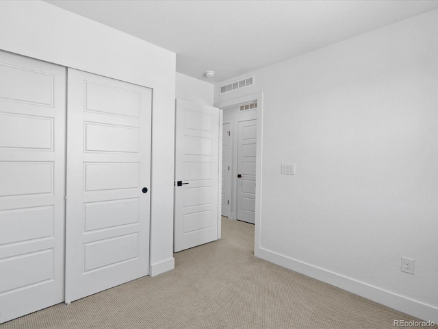 unfurnished bedroom with baseboards, visible vents, a closet, and light carpet