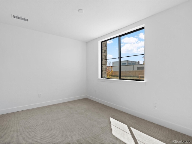 empty room with carpet flooring, baseboards, and visible vents