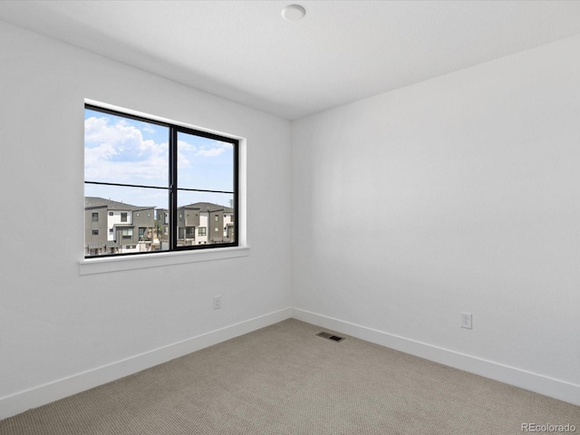 spare room with baseboards, visible vents, and light carpet