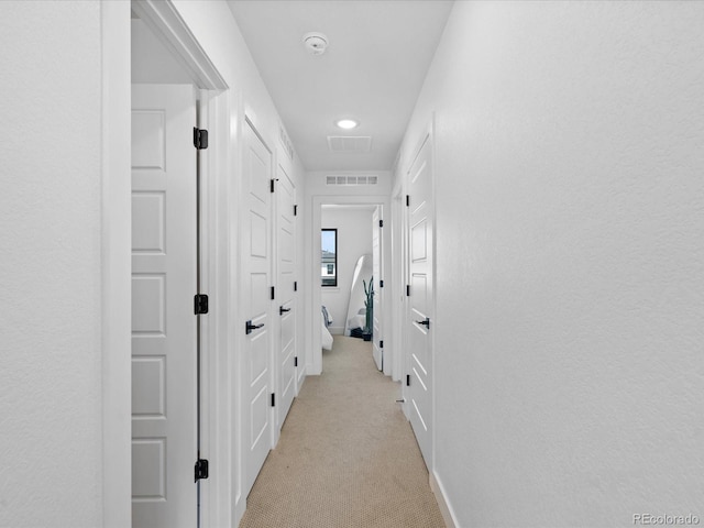 corridor with visible vents and light colored carpet