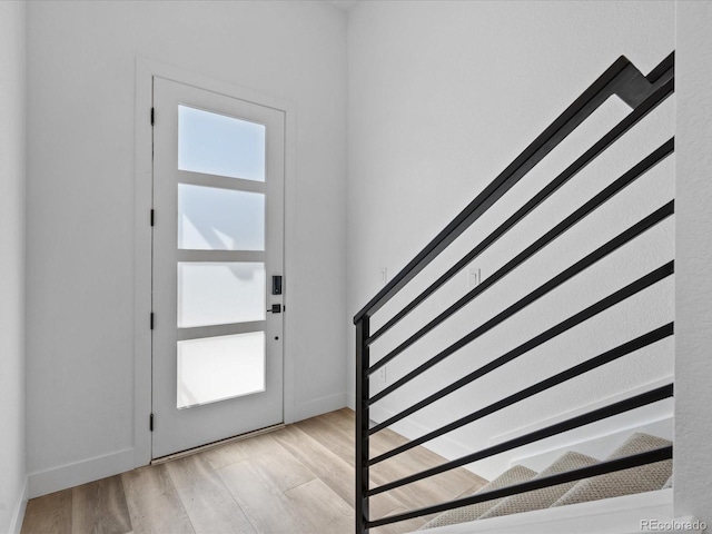 entrance foyer with light wood finished floors, a healthy amount of sunlight, and baseboards