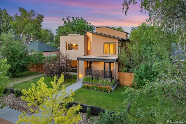 back house at dusk with a lawn