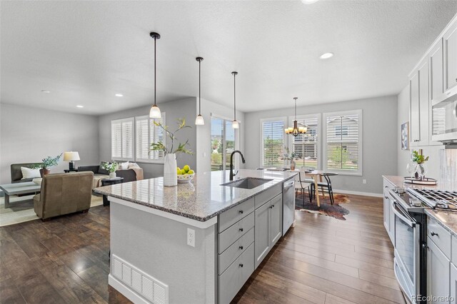 kitchen with sink, dark hardwood / wood-style floors, an island with sink, pendant lighting, and appliances with stainless steel finishes