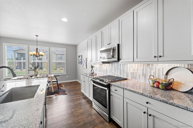 kitchen with dark hardwood / wood-style floors, white cabinetry, stainless steel appliances, and decorative light fixtures