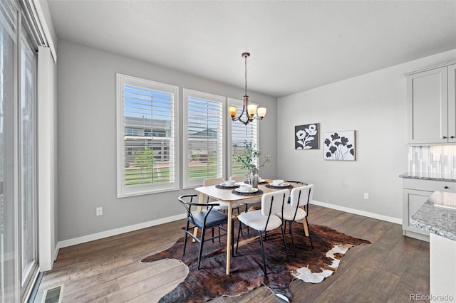 dining space with dark hardwood / wood-style flooring and a notable chandelier