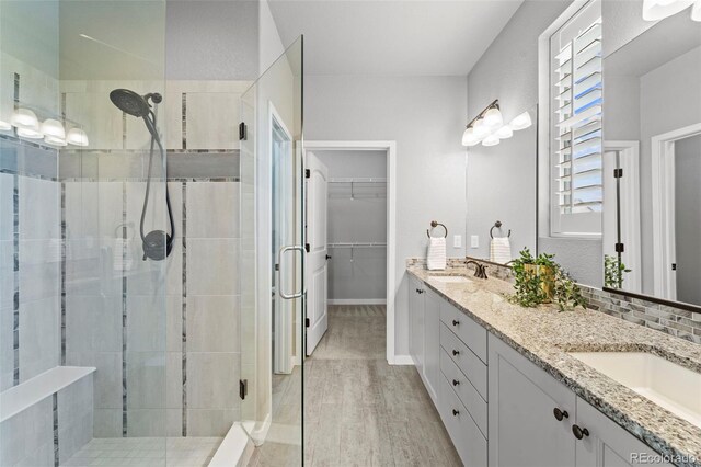 bathroom featuring decorative backsplash, vanity, hardwood / wood-style flooring, and a shower with shower door