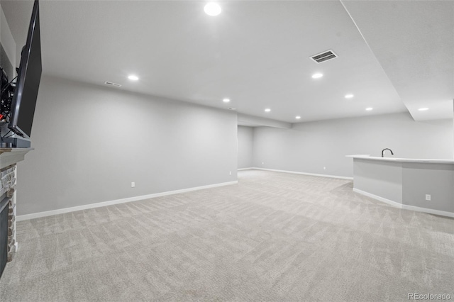 basement featuring a fireplace, light colored carpet, and sink