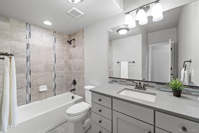 full bathroom with tile patterned floors, vanity, toilet, and tiled shower / bath combo