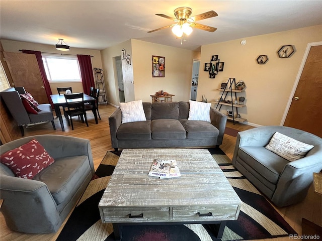 living room with ceiling fan, baseboards, and wood finished floors