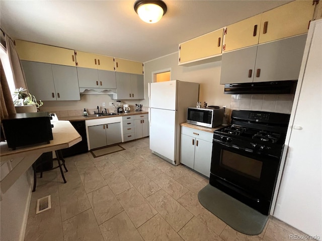 kitchen featuring visible vents, a sink, under cabinet range hood, black appliances, and backsplash