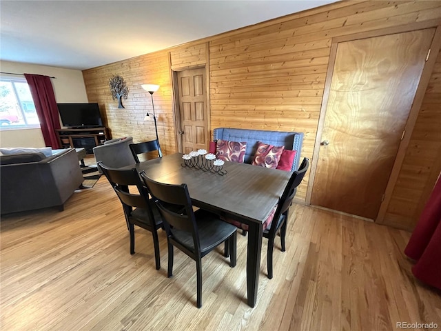 dining area with wood walls and light wood-style flooring