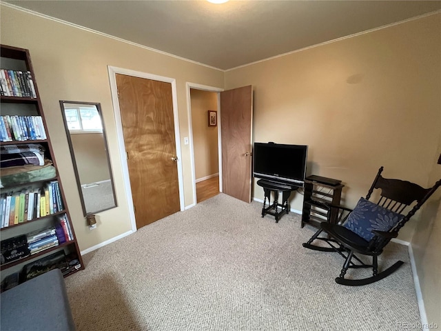 sitting room with baseboards, carpet floors, and crown molding