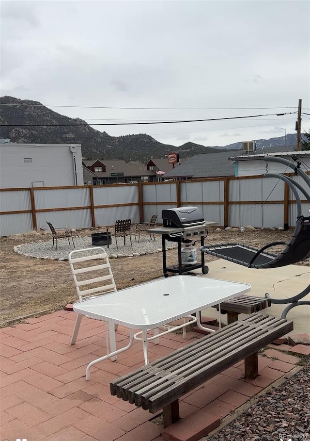 view of patio with grilling area, fence, and a mountain view