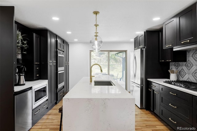 10250 W 33rd Ave, Wheat Ridge, CO 80033 - kitchen featuring a center island with sink, backsplash, light wood finished floors, appliances with stainless steel finishes, and recessed lighting