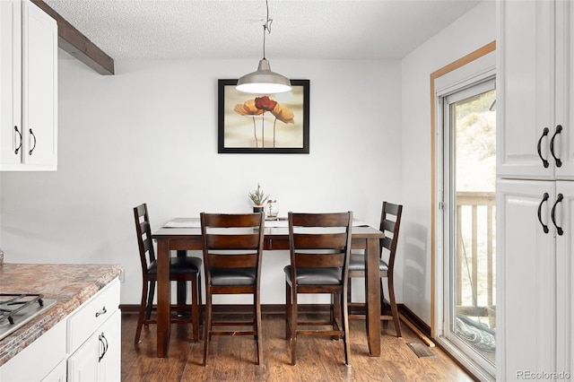 dining room with visible vents, a textured ceiling, and wood finished floors