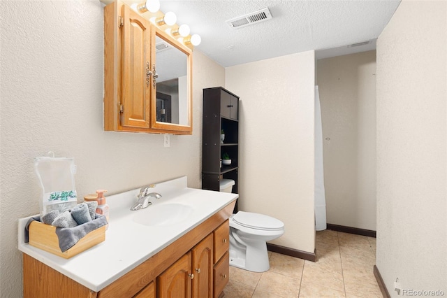 bathroom with tile patterned flooring, vanity, toilet, a textured ceiling, and visible vents