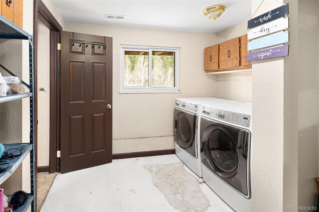 laundry room with baseboards, visible vents, cabinet space, and washer and clothes dryer