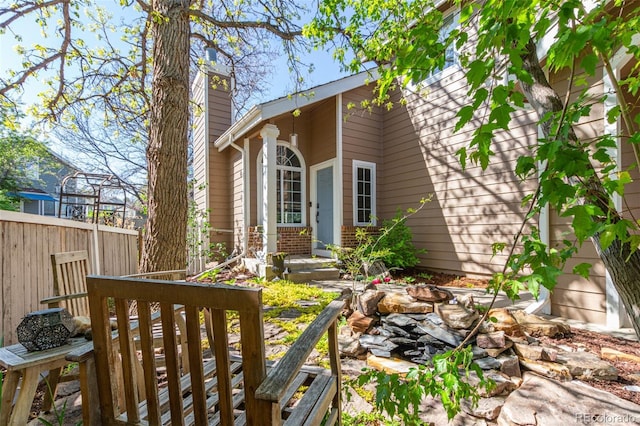 doorway to property with a chimney, fence, and brick siding