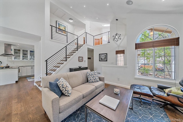 living room with high vaulted ceiling, wood finished floors, stairs, plenty of natural light, and recessed lighting