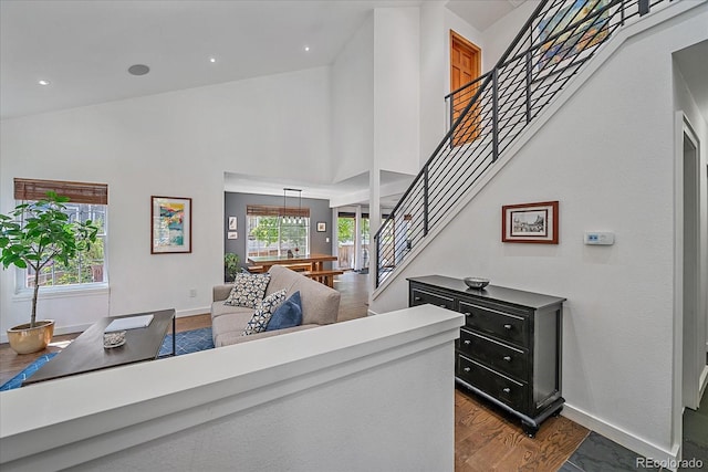 foyer with stairway, baseboards, a high ceiling, and dark wood-style flooring