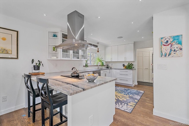 kitchen featuring island exhaust hood, white cabinets, open shelves, a peninsula, and a kitchen bar