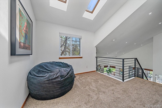 sitting room featuring vaulted ceiling, carpet flooring, baseboards, a skylight, and an upstairs landing