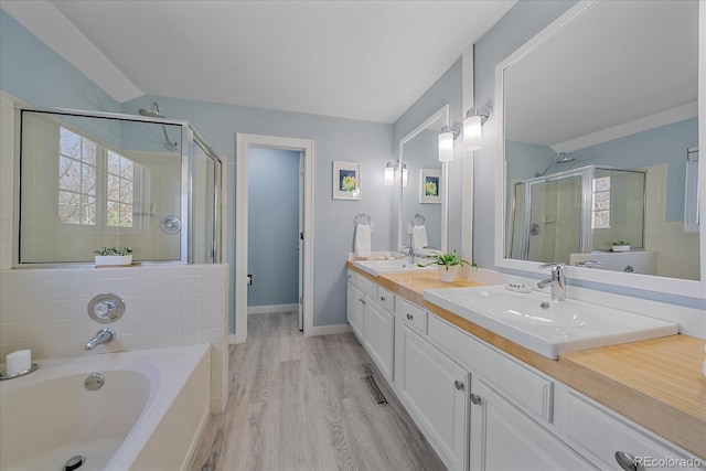 full bathroom with a stall shower, plenty of natural light, a garden tub, and wood finished floors